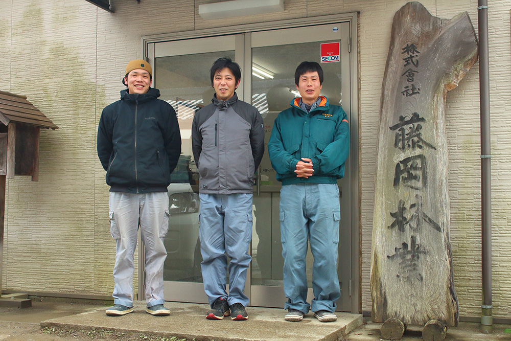 愛媛県内子町にある本社前にて、笑顔で写る社員の皆さん。代表の藤岡さんを囲んで。