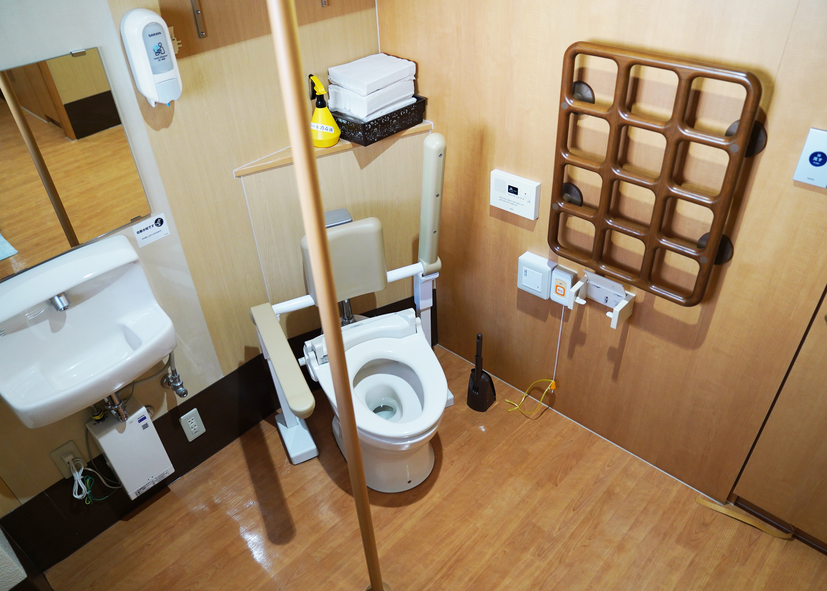 移乗用リフトも使用できるよう扉や手すり、上下する洗面台など、皆の知恵で工夫が施されたトイレ。