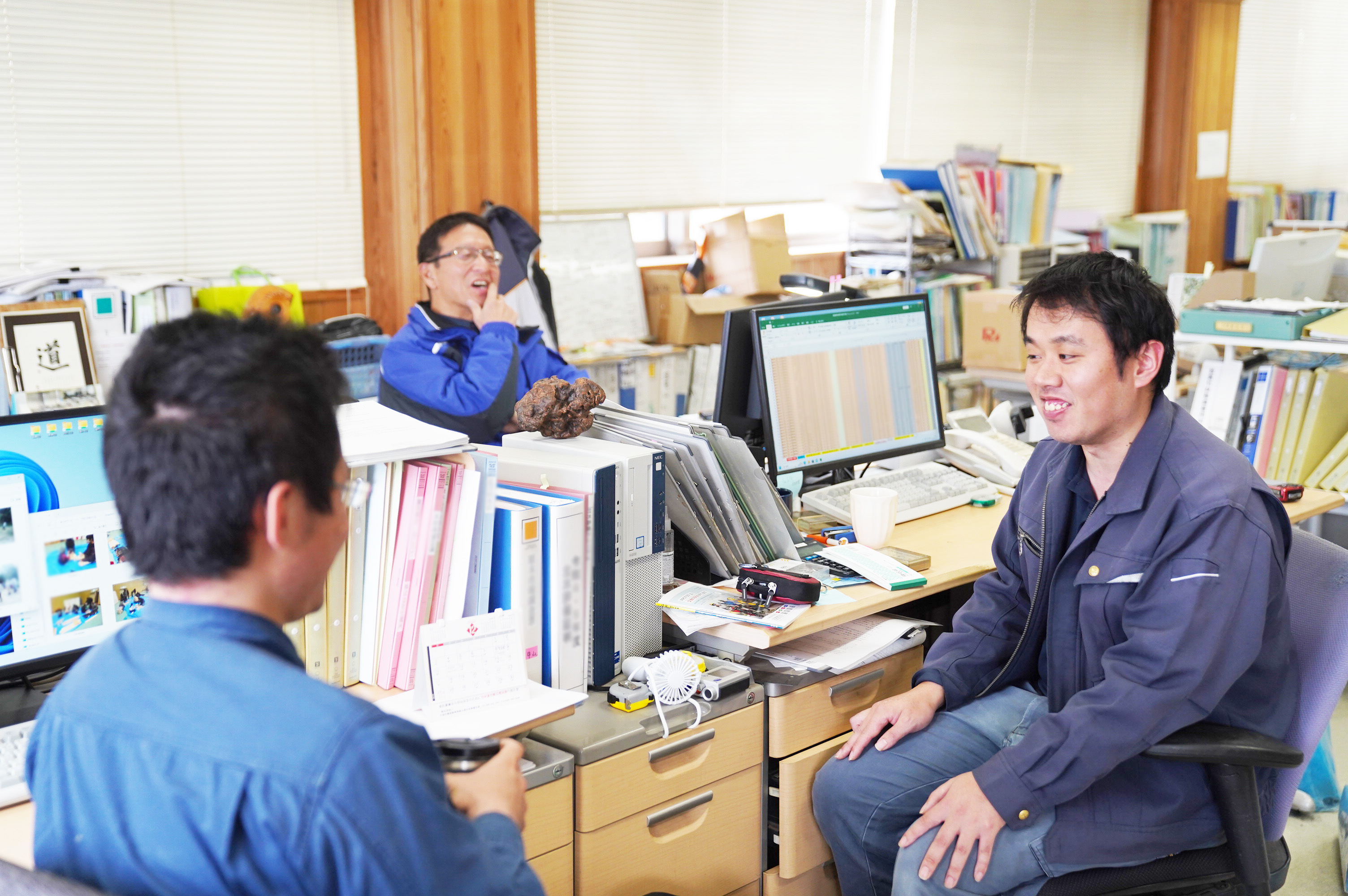 村上さん、妻鳥さん、鈴木さんが、職場で談笑している様子。